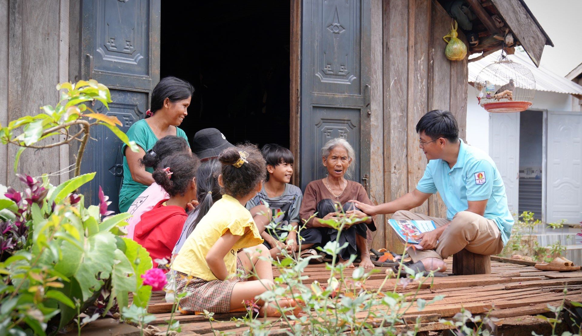 A teacher visits a family sitting outside their home in Viet Nam to explain drowning prevention